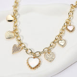 14K gold plated station necklace featuring sparkling CZ paved heart charms and mother of pearl heart accents on a chunky chain on a white background