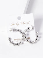 Silver beaded earrings on a 'Lucky Charm' branded card with a white background