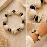 A beaded stretch bracelet with large white and cream marbled beads, deep blue cylindrical beads, and gold-toned spacer rings, shown in a collage with close-up detail shots and a model wearing it on the wrist.