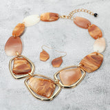 Chunky caramel brown acetate geometric statement necklace and drop earring set on grey textured background