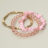 Three-piece blush pink stretch bracelet set featuring natural stone chips, faceted crystal beads, and polished gold accent beads on a light background