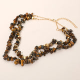 Tiger eye stone chip double layered necklace with gold dipped metallic beads detail on cream background