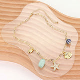 Gold chain necklace with various charms on a wooden surface