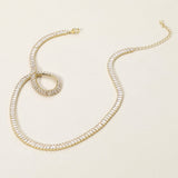Gold necklace with clear gemstones on a beige background