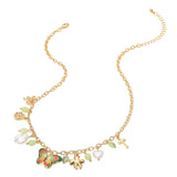 A gold chain necklace featuring a butterfly charm with red, green, and orange enamel, a white pearl, a small green bead, a gold cross, and other small charms, displayed on a clean white background.