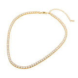 A gold tennis necklace with a continuous row of clear cubic zirconia stones, featuring a lobster clasp and an adjustable extension chain, shown on a plain white background.