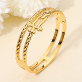 Gold stainless steel double row hinged bangle bracelet featuring sculptural interlock accents and polished finish on a beige background