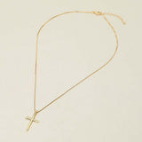 Gold necklace with a cross pendant on a beige background