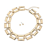 Polished gold geometric rectangle link statement necklace with gold ball stud earrings on white background