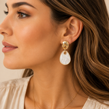 Gold geometric drop earrings featuring polished organic gold-tone studs with white marbled resin dangle accents on a model.
