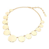 Gold hammered disc link statement necklace with graduated round textured discs and adjustable extender on a beige background