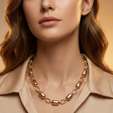 Woman wearing modern gold tone bean link chain necklace with polished pebble and open oval links on neutral background