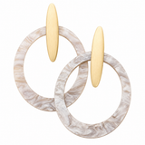 A pair of modern hoop earrings featuring thick, circular marbled white and beige resin hoops with flat, vertical brushed gold post elements, shown on a solid white background.