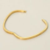 Gold stainless steel square hinged bangle bracelet featuring a sleek minimalist geometric design and polished finish on a beige background