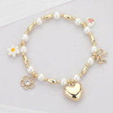 Gold pearl beaded stretch bracelet with heart, bow, flower, and ceramic charm accents