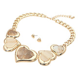 Gold heart-shaped statement necklace with mother-of-pearl inlays, shown with matching stud earrings on a white background.