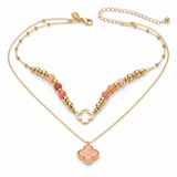 A gold-tone double-layer necklace featuring a top beaded chain with peach and pink beads, a central gold clover motif, and a longer lower chain ending in a peach and gold clover pendant, displayed on a clean white background.
