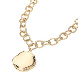 Gold chunky chain necklace with organic round plate pendant and modern statement design on a white background