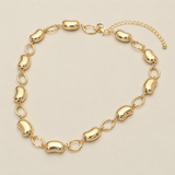 Chunky gold tone bean link station necklace with alternating open oval links displayed on cream background