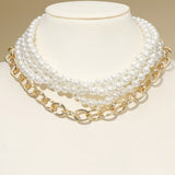 Multi-strand pearl and chunky gold chain necklace set styled together on jewelry bust cream background