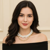 Woman wearing multi-strand pearl choker and chunky gold chain layered necklace set with black off shoulder top