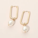 Gold geometric oval huggie hoop earrings with dangling pearl accents for elegant everyday and dressy styling.
