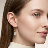 Gold geometric oval huggie hoop earrings with dangling pearl accents for elegant everyday and dressy styling.