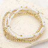 Five-piece pearl and gold beaded stretch bracelet set featuring layered stackable designs with elegant pearl-inspired accents on a beige background