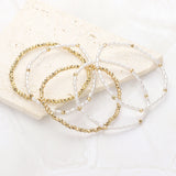 Five-piece pearl and gold beaded stretch bracelet set featuring layered stackable designs with elegant pearl-inspired accents on a white background