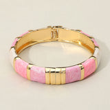 Pink and white enamel bamboo hinged bangle bracelet with gold tone accents and glossy finish on a light beige background