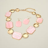 Pink marbled resin octagonal plate and hammered gold disc statement necklace and earring set detail on cream background