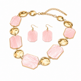 Pink geometric resin plate and hammered gold disc statement necklace with matching drop earrings on white background
