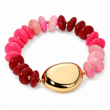 A beaded stretch bracelet featuring polished pink and deep red stone beads separated by small gold spacer beads, with a large smooth gold oval centerpiece, shown on a white background.