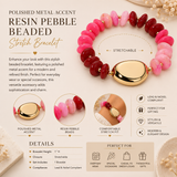 A polished metal accent resin pebble beaded stretch bracelet shown on a beige background with multiple inset detail images and feature callouts. The bracelet features alternating pink, deep red, and light pink oval beads with a polished gold-toned clasp.