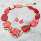 Chunky red acetate geometric statement necklace and drop earring set on grey textured background