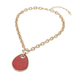 A gold chain necklace featuring a large, irregularly shaped red teardrop pendant with a gold border, displayed on a clean white background.