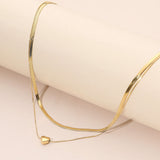 Gold necklace with a heart pendant on a beige background