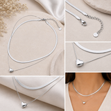 A collage showing a silver double-layered necklace with a heart-shaped pendant, displayed on beige fabric and worn on a model's neck. The collage includes close-up detail shots of the clasp and chain.