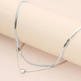 Silver necklace with a heart pendant on a beige background