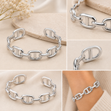 White gold tone SECRET BOX mariner link cuff bracelet luxury detail views. A collage showing a silver chain bracelet with elongated oval links, displayed on a neutral surface and worn on a wrist. The bracelet is shown in multiple close-up panels with a soft beige background and small dried flowers in one corner.