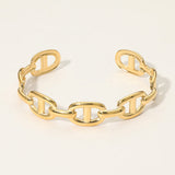 Gold chain bracelet on a light beige background. SECRET BOX stainless steel mariner link cuff bracelet in yellow gold tone.