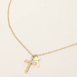 Gold stainless steel double cross pendant necklace with crystal cross charm on a delicate chain on a beige background