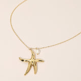 Gold starfish pendant necklace on a beige background
