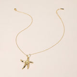Gold starfish pendant necklace on a beige background