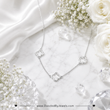 Sterling silver dipped open quatrefoil link station necklace with three elegant clover charms on an adjustable chain displayed on marbled background 