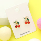 Gold-tone cherry stud earrings with red crystal cherries and green leaf accents on white and yellow background.