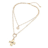 Gold layered necklace featuring a textured cross pendant, round stone charm, and mixed paper clip chain design on a white background
