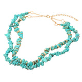 Double layered turquoise natural stone chip bead necklace with gold dipped accent beads and adjustable clasp on a white background