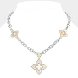 A two-tone silver and gold chain necklace displayed on a white mannequin bust. The necklace features a silver link chain with three gold and silver floral clover-like charms, and a large matching clover pendant with a white inlay.