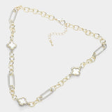 A gold and silver chain necklace featuring four white inlaid clover motifs, displayed on a light gray background.